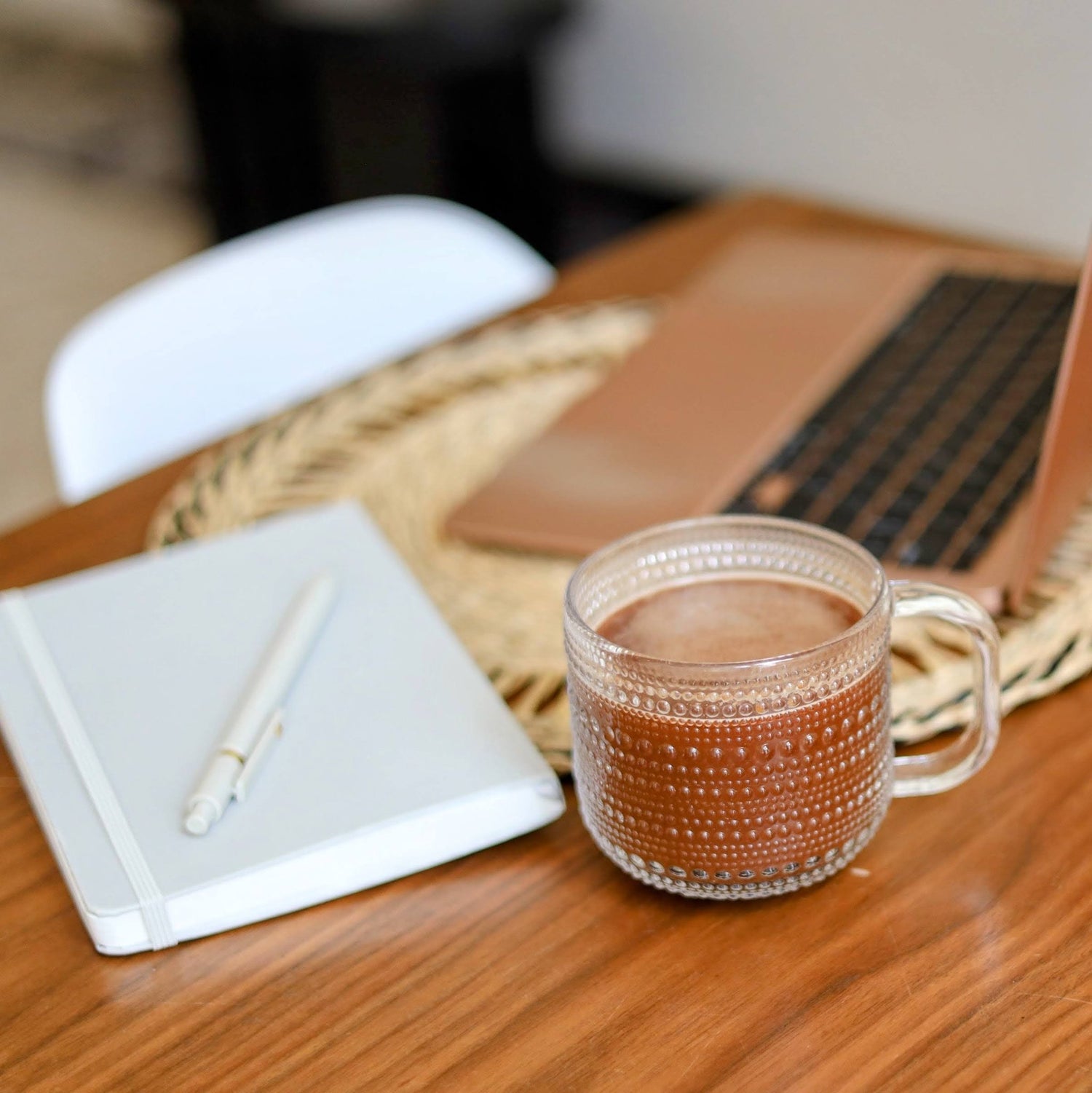 Mug of kapow cacao on a wooden table with a notebook and pen.