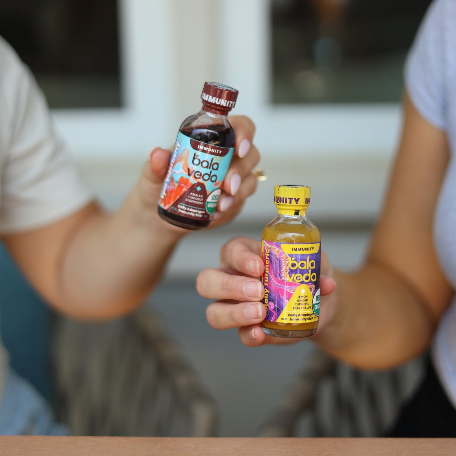 Two people cheering their elderberry and turmeric immunity shots.