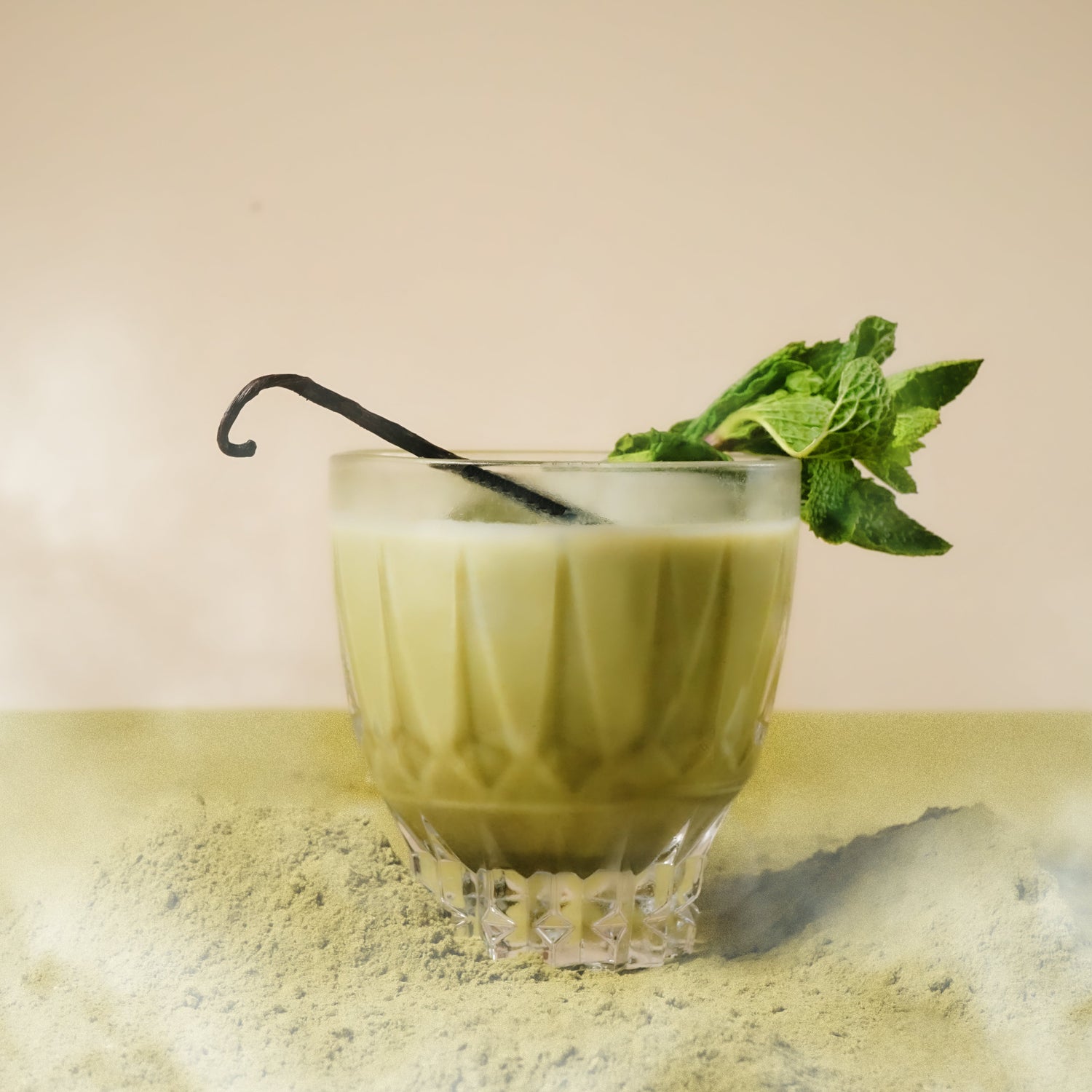 cosmic clarity matcha in a glass with a straw and mint leaf on a textured surface.