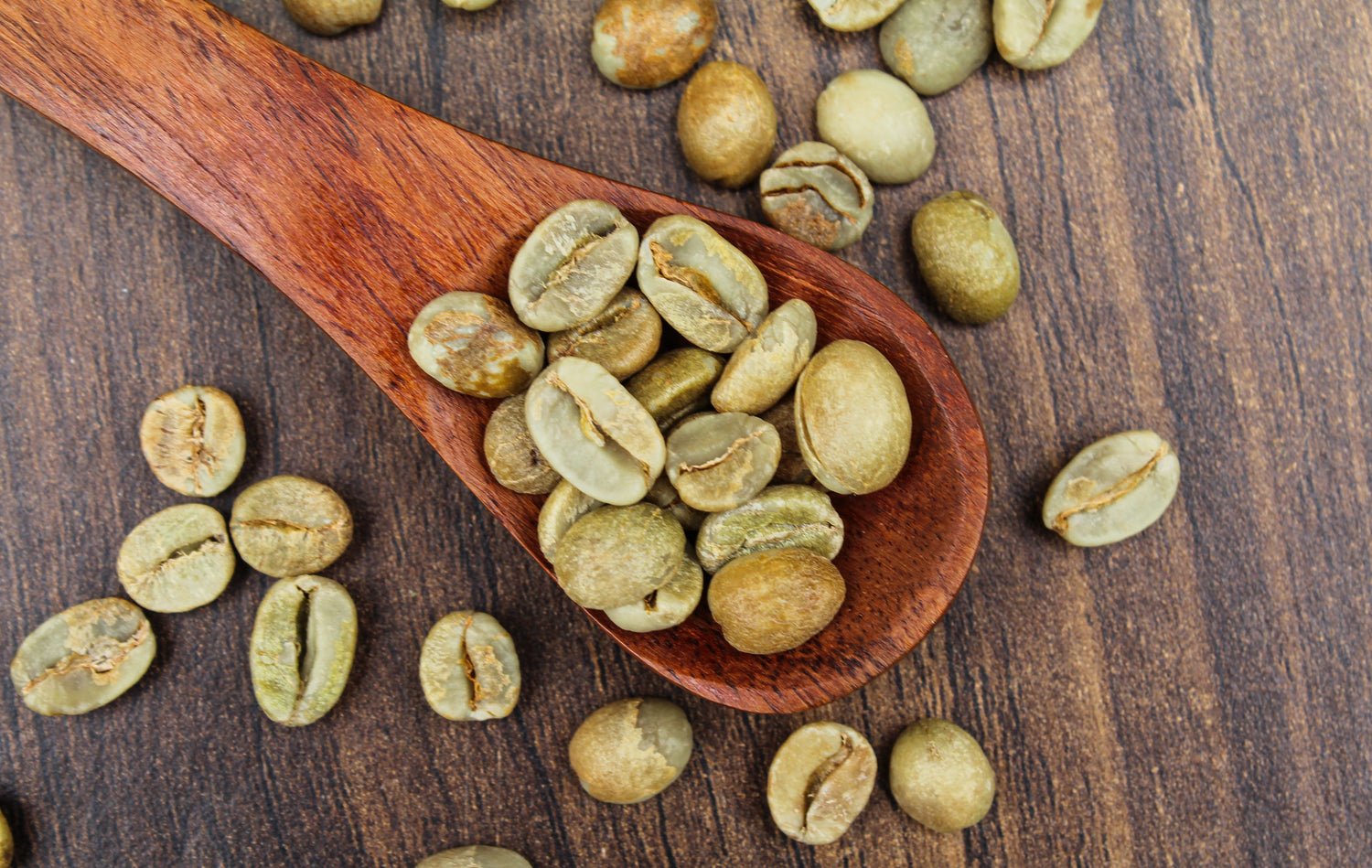 Wooden scoop filled with green coffee beans on a wooden surface