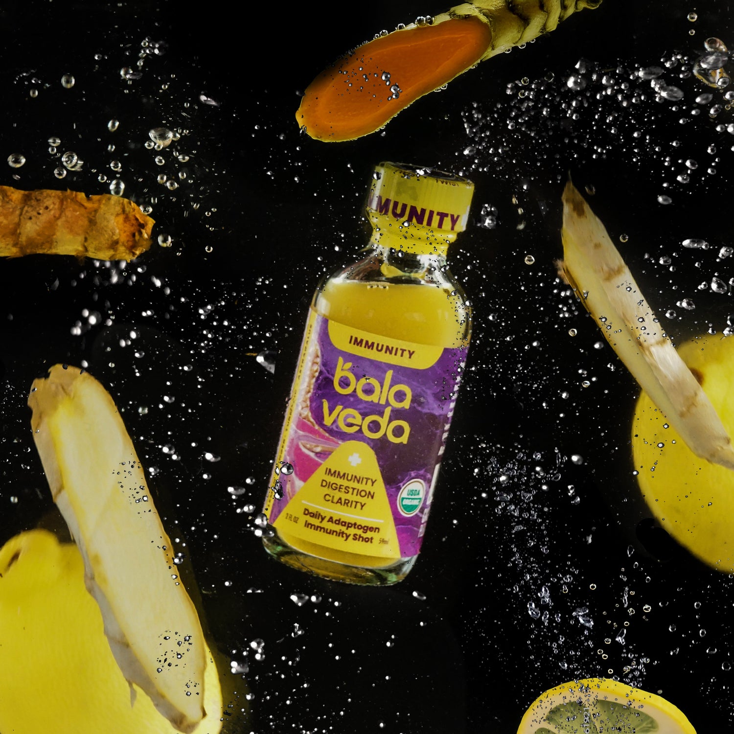 totally turmeric immunity shot bottle surrounded by sliced lemons and turmeric on a dark background