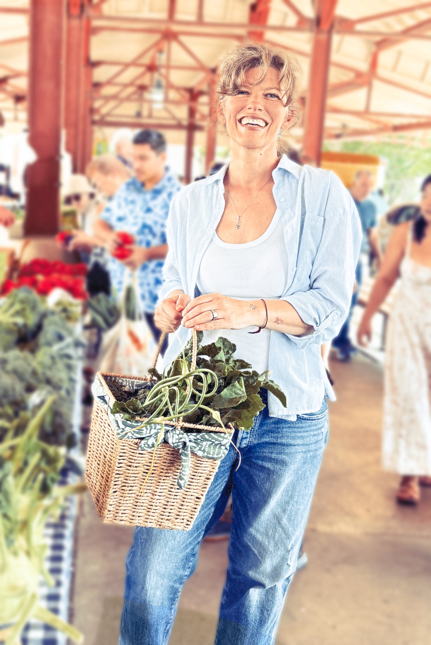 Woman holding a basket of fresh produce at an outdoor market.