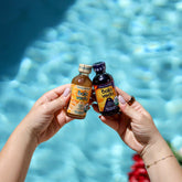 Two bottles of Bala Veda products held up in front of a pool.