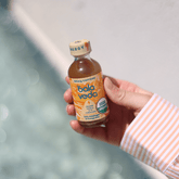 Hand holding a bottle of Bala Veda supersonic citrus energy drink with a blurred background