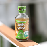 Bala Veda tropic rush energy drink bottle sitting on a rail with blurred background