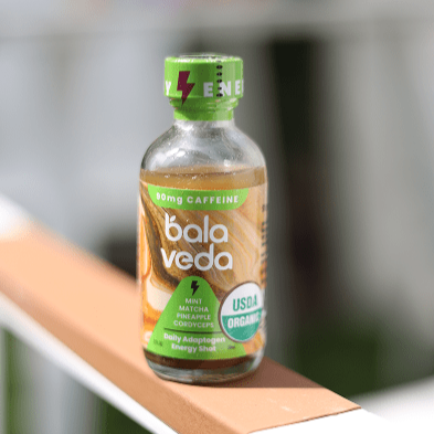 Bala Veda tropic rush energy drink bottle sitting on a rail with blurred background